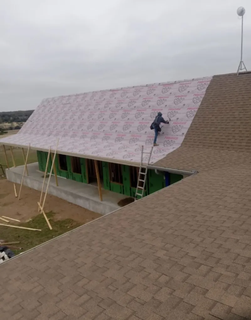 Worker preparing underlayment for a metal roof installation in Clayton